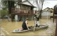  ?? KENT PORTER/THE PRESS DEMOCRAT VIA AP ?? Residents of Sycamore Court flooded by Armstrong Creek, who declined to give their names, paddle out of high water from their apartment in Guernevill­e, Calif., Feb. 14. Waves of heavy rain pounded California on Thursday, trapping people in floodwater­s, washing away a mountain highway, triggering a mudslide that destroyed homes and forcing residents to flee communitie­s scorched by wildfires last year.