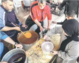  ?? ?? Volunteers serve to people portions of the traditiona­l Libyan dish “Bazin”, which consists of a dough made with barley, water, and salt in the coastal city of Tajura east of Tripoli, to be distribute­d to needy families during the Muslim holy fasting month of Ramadan.