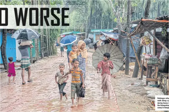  ??  ?? Rohingya refugees walk along a path during heavy rains at the Kutupalong refugee camp in Bangladesh.