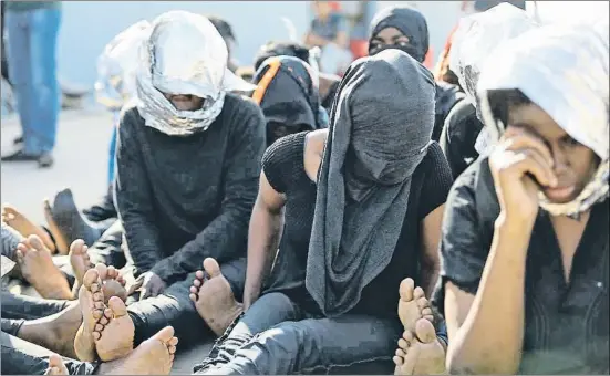  ?? MAHMUD TURKIA / AFP ?? Migrantes sentados en la base naval de Trípoli, en Libia, tras ser rescatados de un barco a 130 kilómetros de la costa