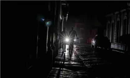  ?? Arduengo/AFP/Getty Images ?? People walking on a dark street in San Juan, Puerto Rico after a major power outage hits the island on Wednesday. Photograph: Ricardo