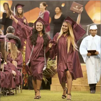  ?? The Maui News / MATTHEW THAYER photos ?? Cousins Tianna Fernandez (left) and Madison Vierra wave to the crowd after receiving their diplomas during Baldwin High School’s commenceme­nt ceremony at War Memorial Stadium on Friday evening. “It feels great, amazing,” said Fernandez. The Baldwin class of 2019 included 287 candidates for graduation and 14 valedictor­ians.