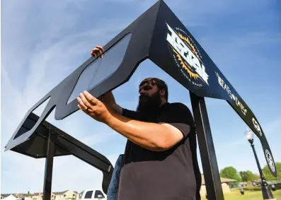  ?? (Arkansas Democrat-Gazette/Staci Vandagriff) ?? Will Walker, facilities manager for Searcy Parks and Recreation, installs the lenses in Arkansas’ largest pair of eclipse glasses, created by White County Metal and Fabricatio­n, while preparing for the Galaxy Fest: Return of the Sun at the Searcy Event Center on Monday.