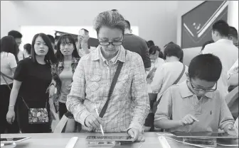  ?? WANG ZHENGWEI / FOR CHINA DAILY ?? Consumers try out iPads at a flagship Apple store in Chengdu, capital of Sichuan province.