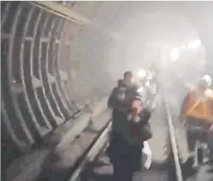  ?? @TYLERPATTA­D TWITTER ?? A passenger posted a video of TTC commuters being safely evacuated through a subway tunnel Monday morning. A small fire started at Dundas West Station, closing the station for three hours.