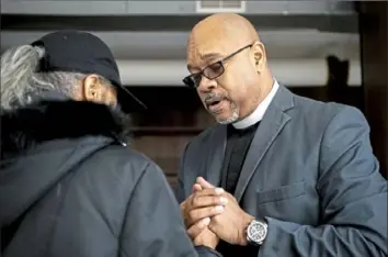  ?? Alexandra Wimley/Post-Gazette photos ?? Rev. Guy Brown, right, of the Church of the Holy Cross, prays with a woman, who declined to be identified, after she surrendere­d a gun Monday and spoke to the minister about her concerns for her son's safety in the community. Visit post-gazette.com for a video report.