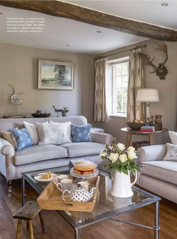  ??  ?? The family room is a relaxed space. Walls have been painted in London Stone by Farrow & Ball. The antlers, mounted on a Black Forest plaque, came from Ardingly antiques fair.