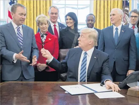  ?? Michael Reynolds European Pressphoto Agency ?? PRESIDENT TRUMP hands a pen to his budget director, Mick Mulvaney, after signing an order Monday reorganizi­ng the executive branch. Mulvaney says Trump’s preliminar­y spending plan, to be released Thursday, will cut most department­s by 10% to 12%.