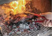  ?? Kin Man Hui / Staff photograph­er ?? Flames ignite as Bandit BBQ owner and pitmaster Brandon Peterson places a cut of beef tri-tip on top of hot coals. “Tri-tip is very close in flavor” to brisket, he says.