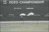  ?? The Associated Press ?? NO SPECTATORS: People hold umbrellas in the rain as they walk past near the practice area Friday after the second round of the Zozo Championsh­ip PGA Tour is postponed due to heavy rain at the Accordia Golf Narashino country club in Inzai, east of Tokyo, Japan.