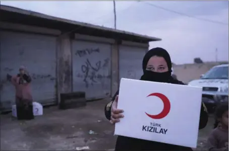  ?? THE ASSOCIATED PRESS ?? A woman carries aid being distribute­d Saturday by the Turkish Red Crescent in Ras Al-Ayn, Syria. Turkish Red Crescent says it has delivered humanitari­an aid for 2,000 people in Ras Al-Ayn.