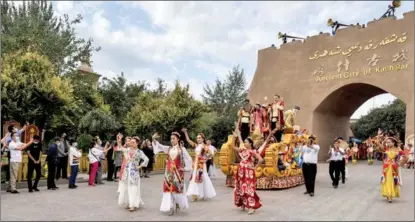  ?? MA KAI / XINHUA ?? Tourists watch a dance performanc­e in the Old Town in Kashgar, Xinjiang Uygur autonomous region.