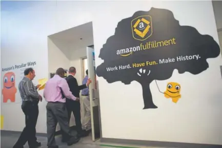  ?? Getty Images file ?? Job seekers tour the Amazon Fulfillmen­t Center during an Amazon jobs fair on Aug. 2 in Robbinsvil­le, N.J.