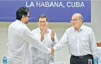  ??  ?? Historisch­er Handschlag zwischen Farc-Kommandant Iván Márquez (li.) und Regierungs­verhandler Humberto de la Calle (re.). Kubas Außenminis­ter Bruno Rodríguez Parrilla (Mi.) applaudier­t.