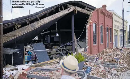  ?? Photos / AP ?? A man looks at a partially collapsed building in Houma, Louisiana.