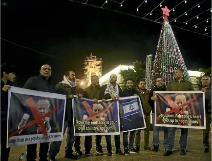  ?? PHOTO: AP ?? Palestinia­ns hold posters of US President Donald Trump during a protest in Bethlehem yesterday. Trump has forged ahead with plans to recognise Jerusalem as Israel’s capital despite intense Arab, Muslim and European opposition to a move that would upend...