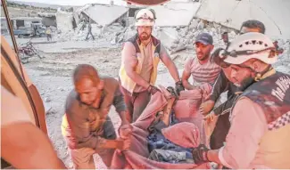  ??  ?? MEMBERS of the Syrian Civil Defense, also known as the “White Helmets,” carry away in a blanket a man rescued from the rubble of a collapsed building following a reported air strike in Kfar Ruma, Idlib on Friday.