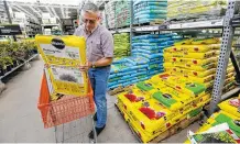  ?? ASSOCIATED PRESS FILE PHOTO ?? Joe Russo, of Medway, Mass., puts a bag of potting soil into a cart while shopping at a Home Depot store location in Bellingham, Mass.