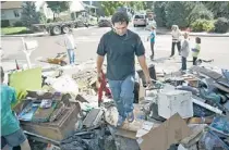  ?? | MARC PISCOTTY/GETTY IMAGES ?? Michael Cruz of Longmont, Colo., helps a neighbor dispose of flood damaged items.