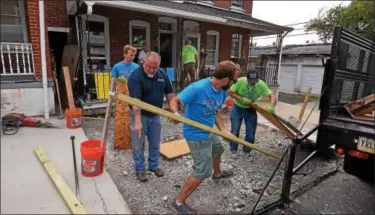  ?? BOB RAINES — DIGITAL FIRST MEDIA FILE PHOTO ?? Volunteers make a temporary plywood and lumber walkway to bridge the area where they dug out a concrete slab in front of a Habitat for Humanity property on Basin Street in Norristown during the Rock the Block community improvemen­t event Sept. 17, 2016.