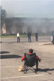  ?? CITIZEN STAFF PHOTO ?? A man sits on a lawn chair to watch the Econo LodgE firE.