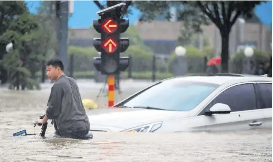  ?? (Photo: AP) ?? A man rides a bicycle through a flooded intersecti­on in Zhengzhou in central China’s Henan Province, on Tuesday.