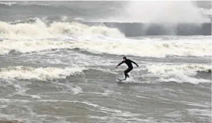  ??  ?? A surfer braves the wind and rain at Criccieth beach last week amid stormy conditions