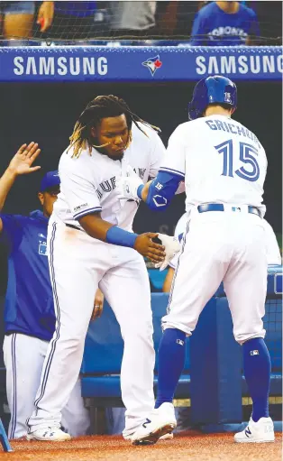  ?? VAUGHN RIDLEY/GETTY IMAGES ?? Randal Grichuk, right, of the Toronto Blue Jays celebrates with teammate Vladimir Guerrero Jr. after hitting a solo home run against the Texas Rangers at Rogers Centre on Tuesday.