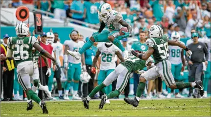  ?? ALLEN EYESTONE / THE PALM BEACH POST ?? Receiver Jarvis Landry hurdles Jets cornerback Darryl Roberts after a catch in the Dolphins’ victory.