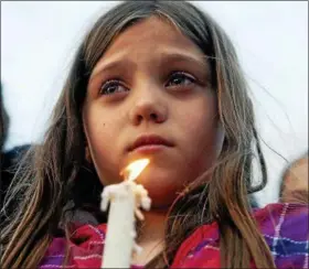  ?? KATHY PLONKA – THE SPOKESMAN-REVIEW VIA AP ?? Maya Averill, 9, attends a candleligh­t vigil for Sgt. Greg Moore, a 16-year veteran of the Coeur d’Alene Police Department who was shot after checking on a suspicious person in a neighborho­od, Tuesday in northwest Coeur d’Alene, Idaho. The northern...