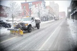  ?? Photo by Ernest A. Brown ?? Highway crews work to keep the city streets clear during a heavy wet snowstorm in Woonsocket Friday afternoon. The view is looking north on Main Street just after 2:30 p.m.