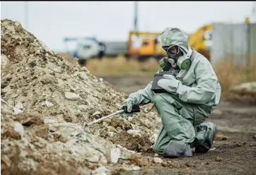  ?? ?? A RADIATION SPECIALIST, sporting protective clothing and a gas mask, uses a Geiger counter to check the level of radioactiv­e radiation in Chernobyl’s “danger zone.”