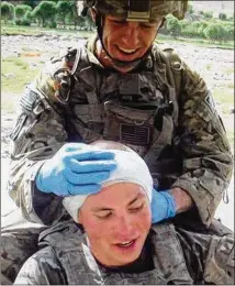 ?? PHOTO CONTRIBUTE­D ?? Former U.S. Army soldier Chris Weakley performs first aid on a security officer who had been stabbed in the head. Weakley, 33, is now a student at Emory University, majoring in finance.