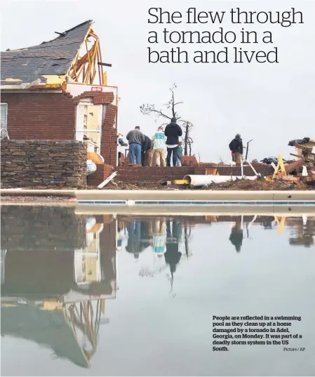  ?? Picture / AP ?? People are reflected in a swimming pool as they clean up at a home damaged by a tornado in Adel, Georgia, on Monday. It was part of a deadly storm system in the US South.