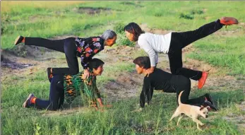  ??  ?? Four villagers practice yoga in the field early in the morning.