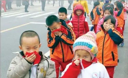  ?? AFP ?? Pupils from an elementary school cover their mouths and noses as they leave the schoolyard after the classes were suspended because of a ‘red alert’ for heavy smog in Binzhou, east China’s Shandong province, on December 15, 2015.