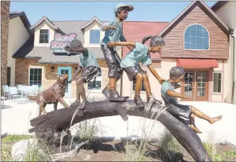  ?? LYNN KUTTER ENTERPRISE-LEADER ?? A new sculpture installed in front of the Farmington Village on Main Street in Farmington shows children of different races and ethnicitie­s playing together with their puppy on a log.