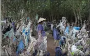  ?? NHAC NGUYEN — GETTY IMAGES ?? A Vietnamese woman gathers shells in a coastal forest littered with plastic waste stuck in branches after it was washed up by rising coastal tides in 2018.