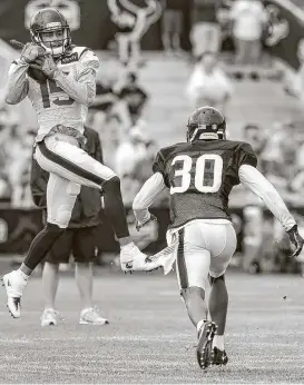  ?? Brett Coomer / Houston Chronicle ?? Texans cornerback Kevin Johnson, right, can do little but watch as wide receiver Will Fuller makes a catch in training camp. But by breaking his collarbone Wednesday, Fuller will be doing the watching for the next two to three months.