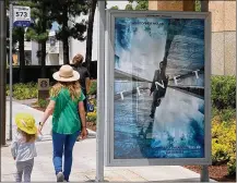  ?? ANTHONY MCCARTNEY / AP ?? People walk by a poster promoting the long-awaited film “Tenet” in Los Angeles. The film has delayed its premiere again and Warner Bros. may stagger its eventual release.