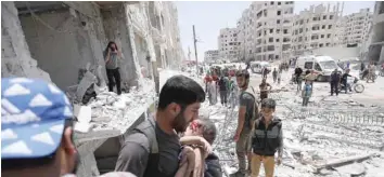  ?? — AFP ?? A man carries a wounded child out of a building following a car bomb explosion in Idlib on Saturday.