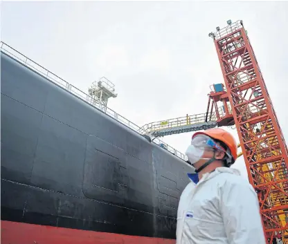  ?? /China Daily via Reuters ?? Appetite for
fuel: A dock worker wearing a face mask to prevent the spread of the coronaviru­s looks at a tanker unloading crude oil at a port in Qingdao, Shandong province, in China.