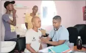  ??  ?? CARING: Dr Terrence Moodley examines Sacrament Ntuli before giving him his daily methadone dose at the TB HIV Care Centre in Umbilo. Looking on are Njabulo Gumede, who sought help after using heroin for three months, and Nhlakaniph­o Msomi, who started...