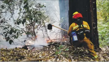  ?? RANDY VAZQUEZ — STAFF PHOTOGRAPH­ER ?? A Redwood City Fire Department firefighte­r cuts a fire break near a home on Debby Lane in Boulder Creek on Monday.