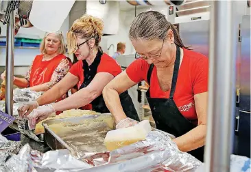  ??  ?? Volunteers, including Tammy Walker, right, and Tricia Henderson-Ferguson, prepare food Thursday for a community Thanksgivi­ng meal at the Salvation Army Chesapeake Energy Center of Hope, 1001 N Pennsylvan­ia, in Oklahoma City.