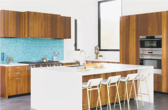  ?? Photograph­y by Suzanna Scott Photograph­y ?? Above: The kitchen of this Mill Valley home features bookmatche­d cabinetry, a stone island with waterfall edges and a glass tile backsplash. Below left: Floor-to-ceiling sliding doors frame views of the Mill Valley landscape in this home designed by...