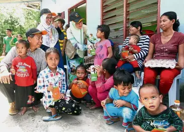  ??  ?? Caring group: MyCare members – Kamarul Zaman, Roha and Dr Fauziah – getting to know the orang asli of Perkampung­an Orang Asli Hulu Kemensah prior to the start of Ramadan.