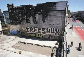  ?? Michael Macor / The Chronicle ?? A gaping hole and charred structure are all that remain of the former Cole Hardware on a busy block of Mission Street, after a fire a year ago displaced eight businesses and 58 people.