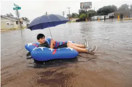  ?? Gerald Herbert / Associated Press ?? Julius Verret, 14, floats in street flooding in Lake Charles as the southwest Louisana city receives heavy rains from Tropical Storm Harvey.