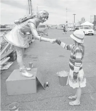  ??  ?? “Living statue” Jenny Jupiter shakes hands with Charlotte Moysey, 9, at Ship Point.